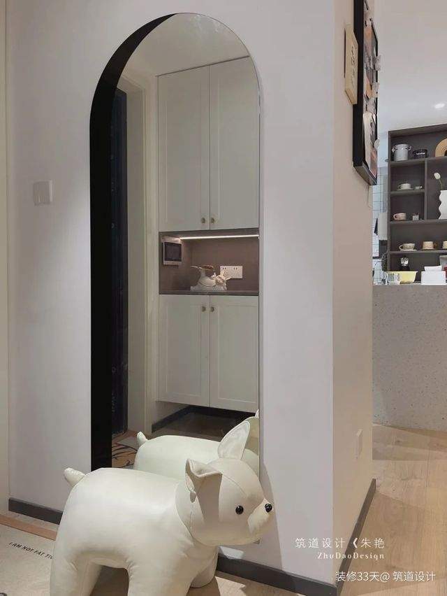 玄關設置了拱形穿衣鏡和狗狗換鞋凳，從鏡子裡可以看到分體式鞋櫃，櫃體中間增設感應燈帶，提升歸家氛圍感
