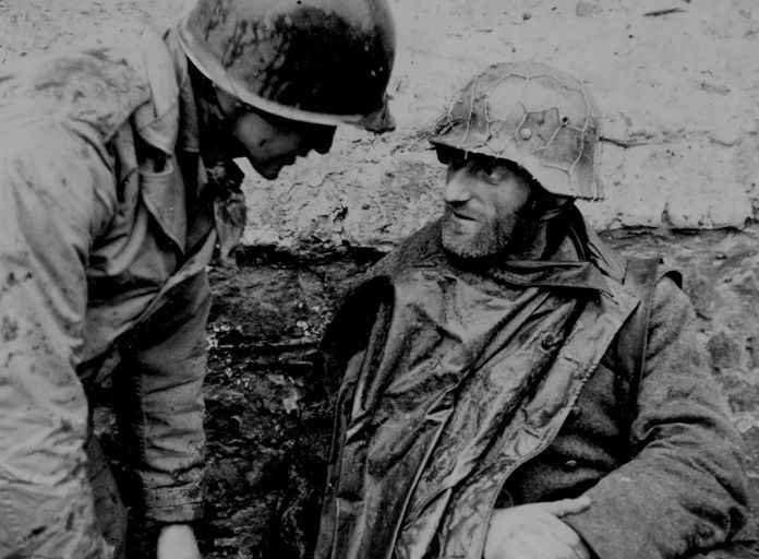 美軍士兵正在訊問身披雨衣的德軍士兵