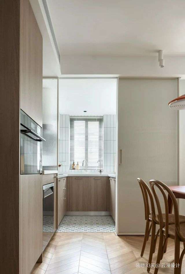 廚房採用長虹玻璃移門隔斷，運用魚骨拼木地板與花磚地面拼接過渡