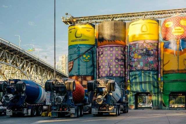 在混凝土卡車和格蘭維爾大橋的映襯下，由Os Gemeos創作的溫哥華雙年展作品巨人(Giants)被